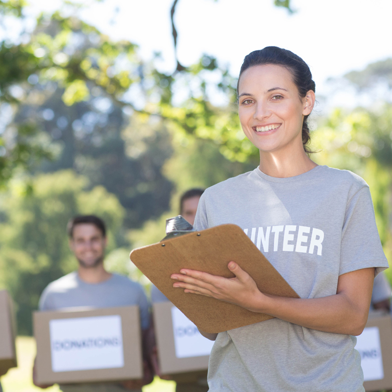 Woman holding clipboard with volunteers behind her