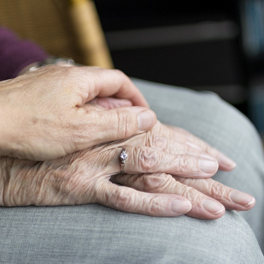 Caregiver holding hand of older adult