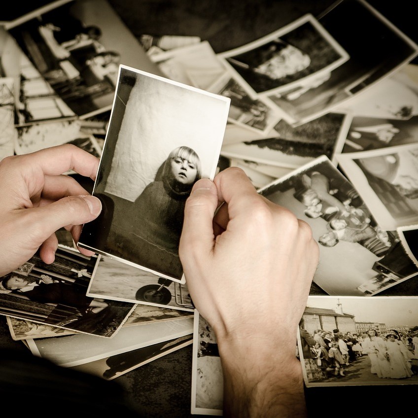 Man holding black and white photo with many scattered
