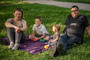 Mom, Dad, 2 kids sitting on a blanket outside