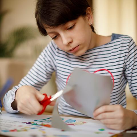 Teen cutting paper at table