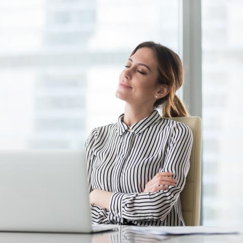 Women sitting at her desk with arms crossed and eyes closed