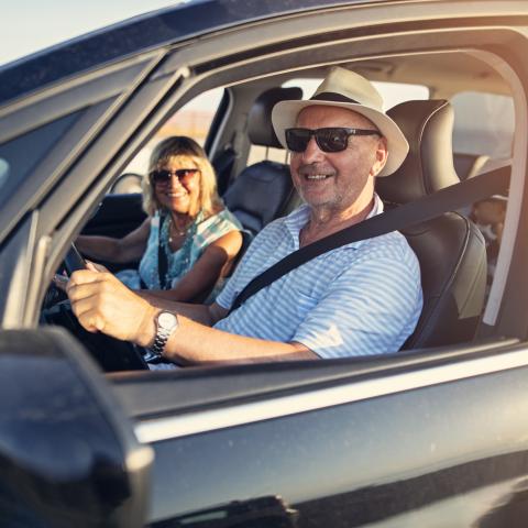 Couple driving car with windows down