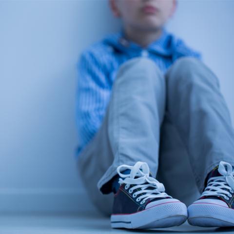 Sad child sitting on floor