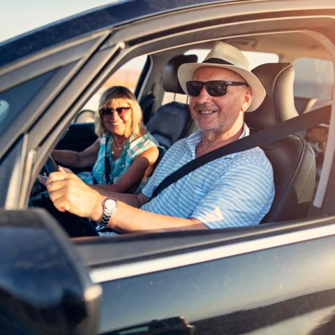 Couple driving car with windows down
