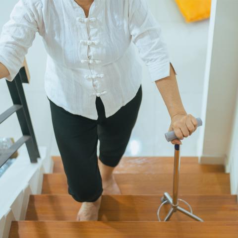 Senior woman walking up stairs with cane