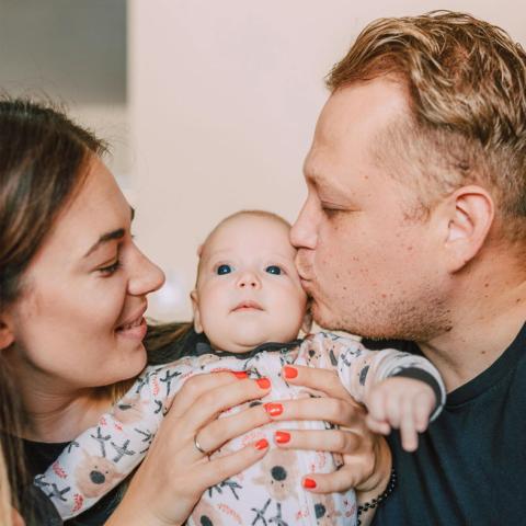 Mom and dad kidding baby's cheek