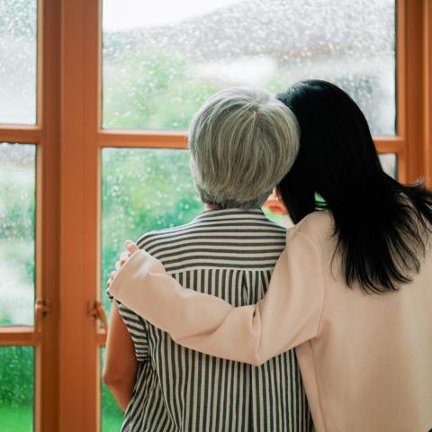 Senior woman and caregiver looking out window