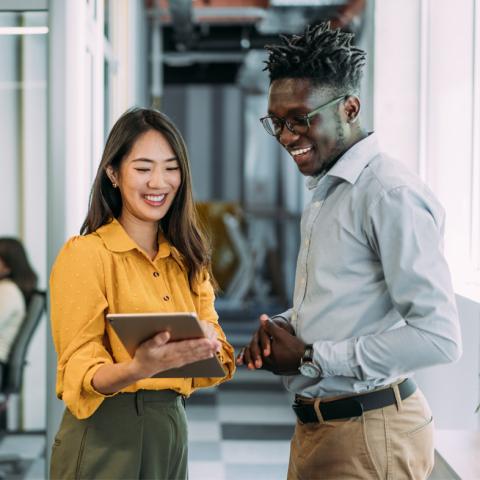 Coworkers looking at iPad smiling