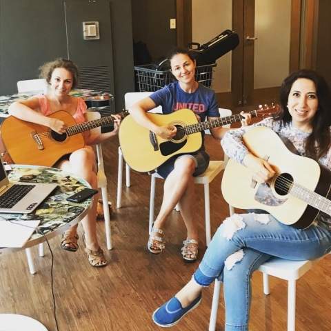 3 young women playing acoustic guitars