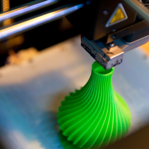 3D printer printing a green vase