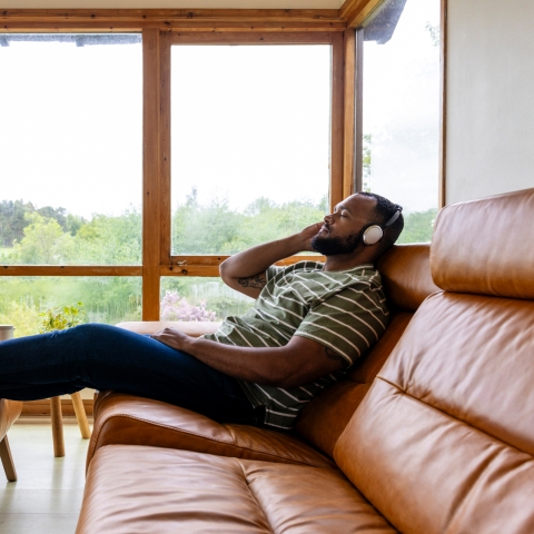 Man laying on couch with eyes closed and headphones on