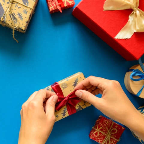 Hand wrapping gift on a blue background