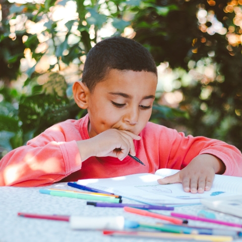 Boy drawing outside with colored pencils