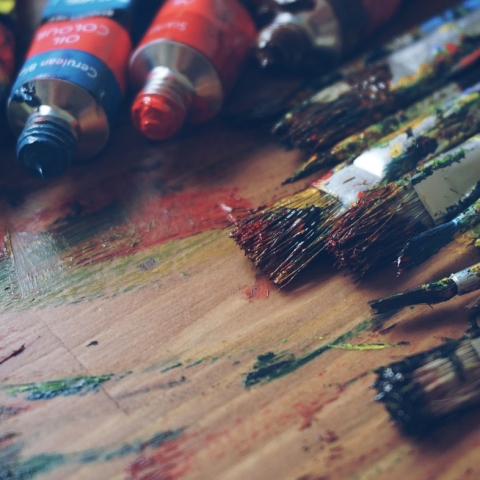 Paints and paint brushes on wooden table