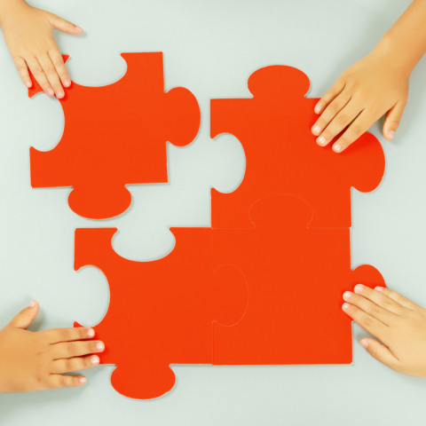 Hands reaching for orange puzzle pieces