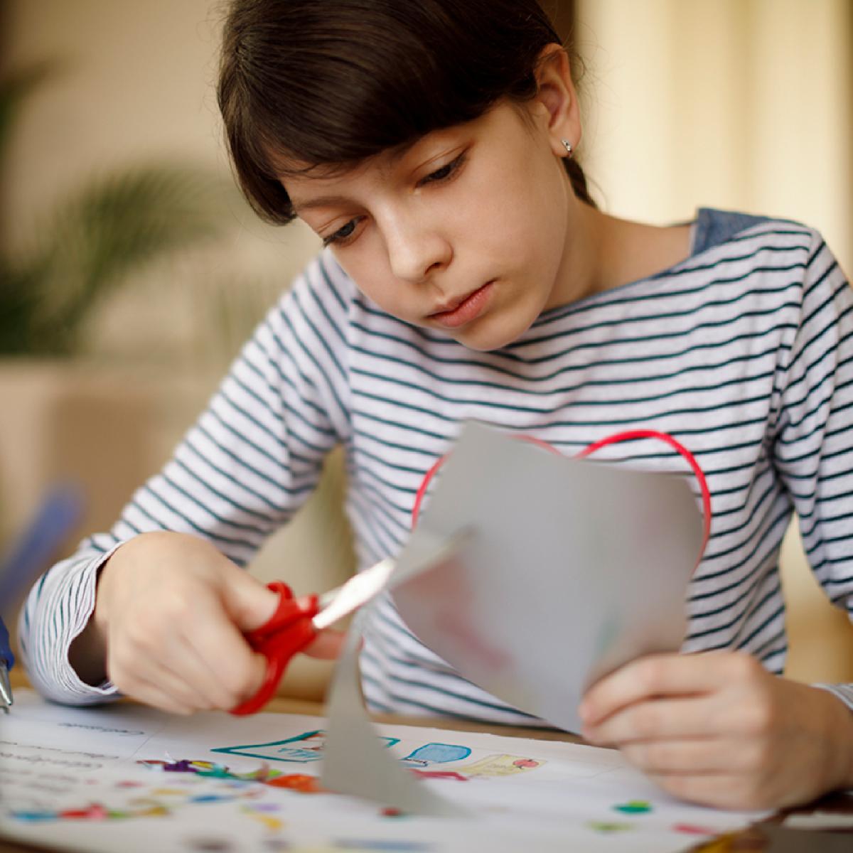 Teen cutting paper at table