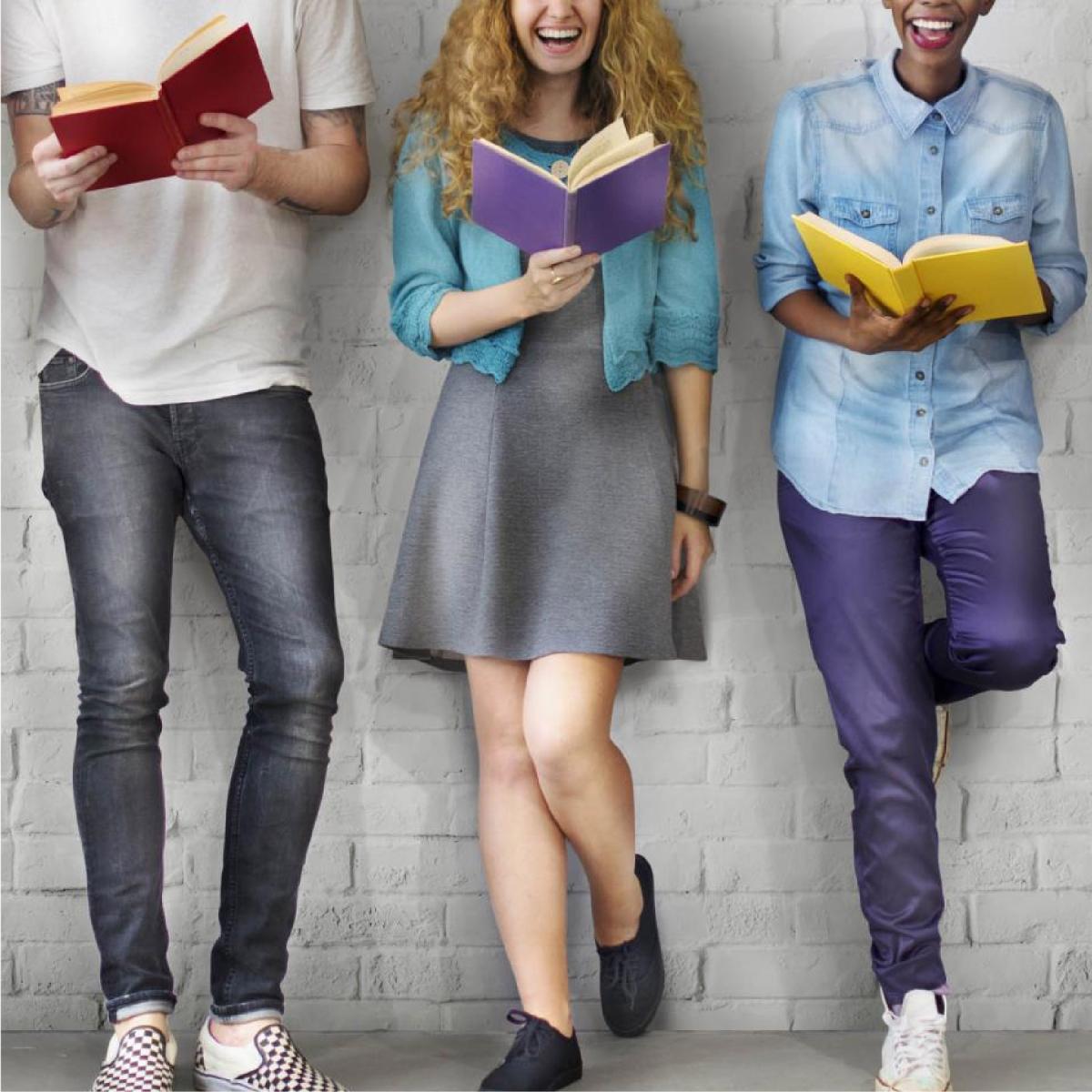 teens sitting on a wall reading