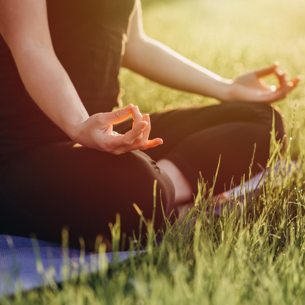 Person meditating in the grass