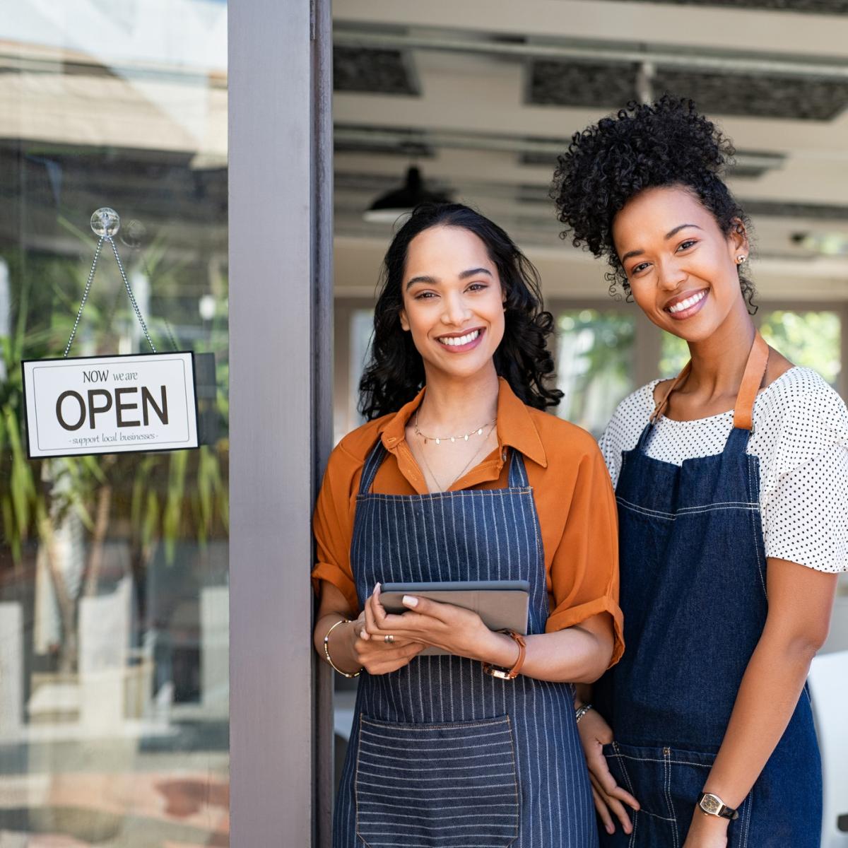 Two women outside their shop wearing aprons