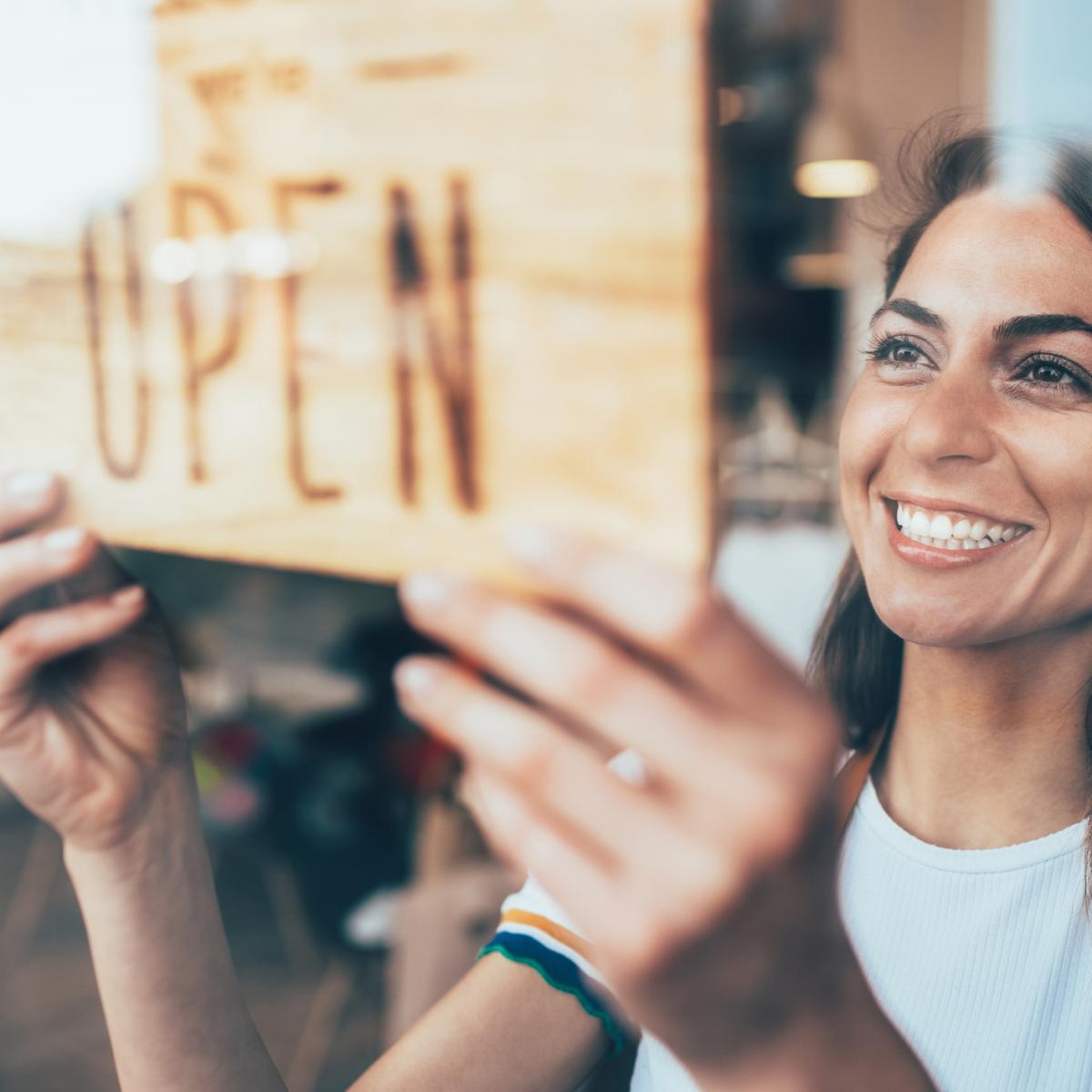 Woman flipping sign on door to "open"