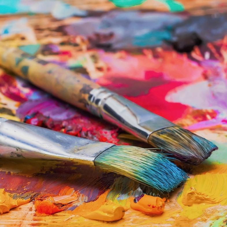 Two paint brushes on top of acrylic paint