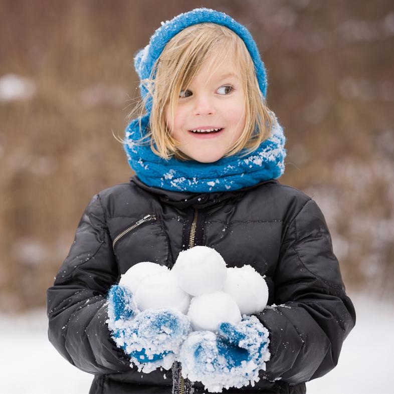 Young boy holding snowballs
