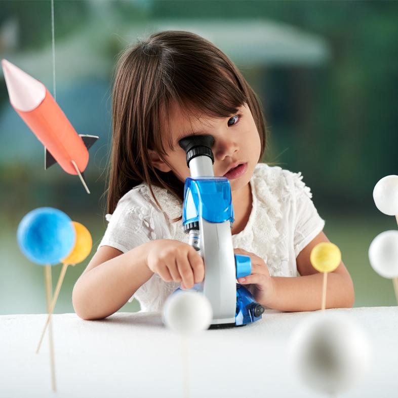Preschool girl looking through microscope