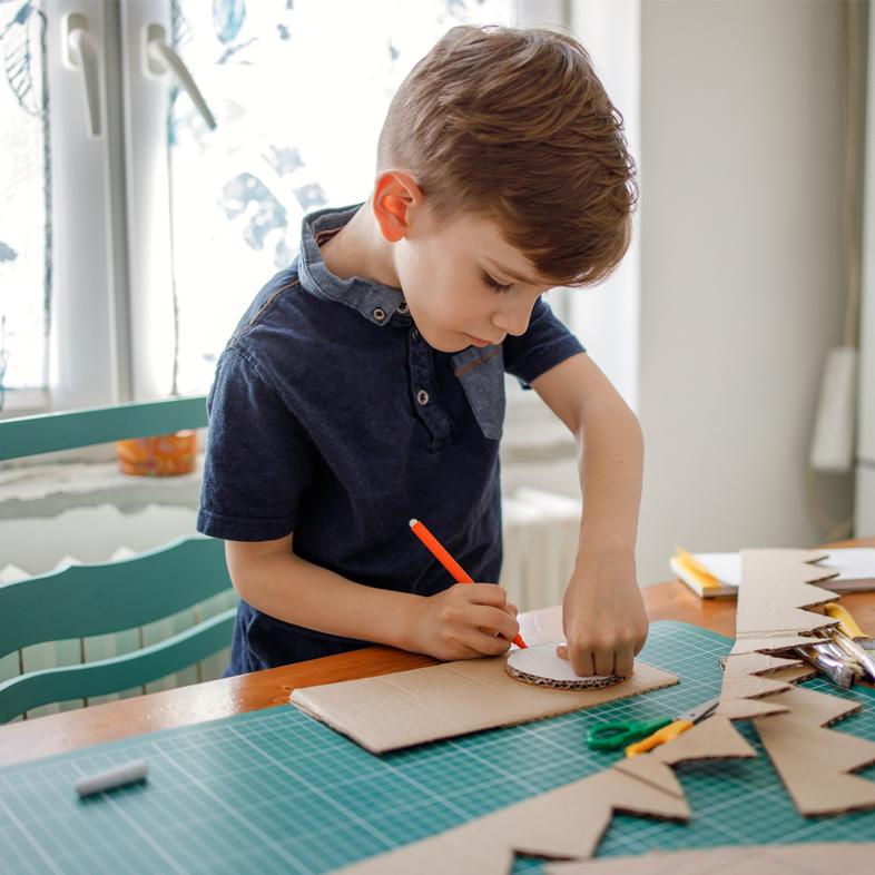 Elementary boy tracing cardboard circle