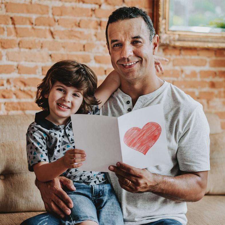 Father and son posing with card