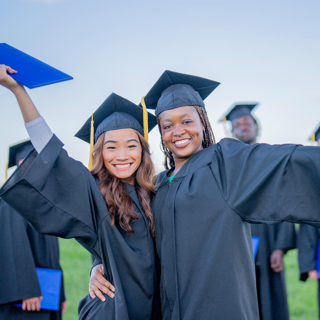 Two graduates hugging and smiling