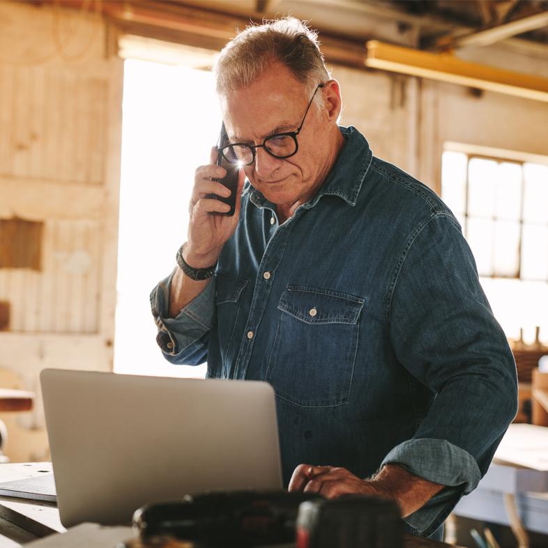 Senior working on a computer and talking on phone