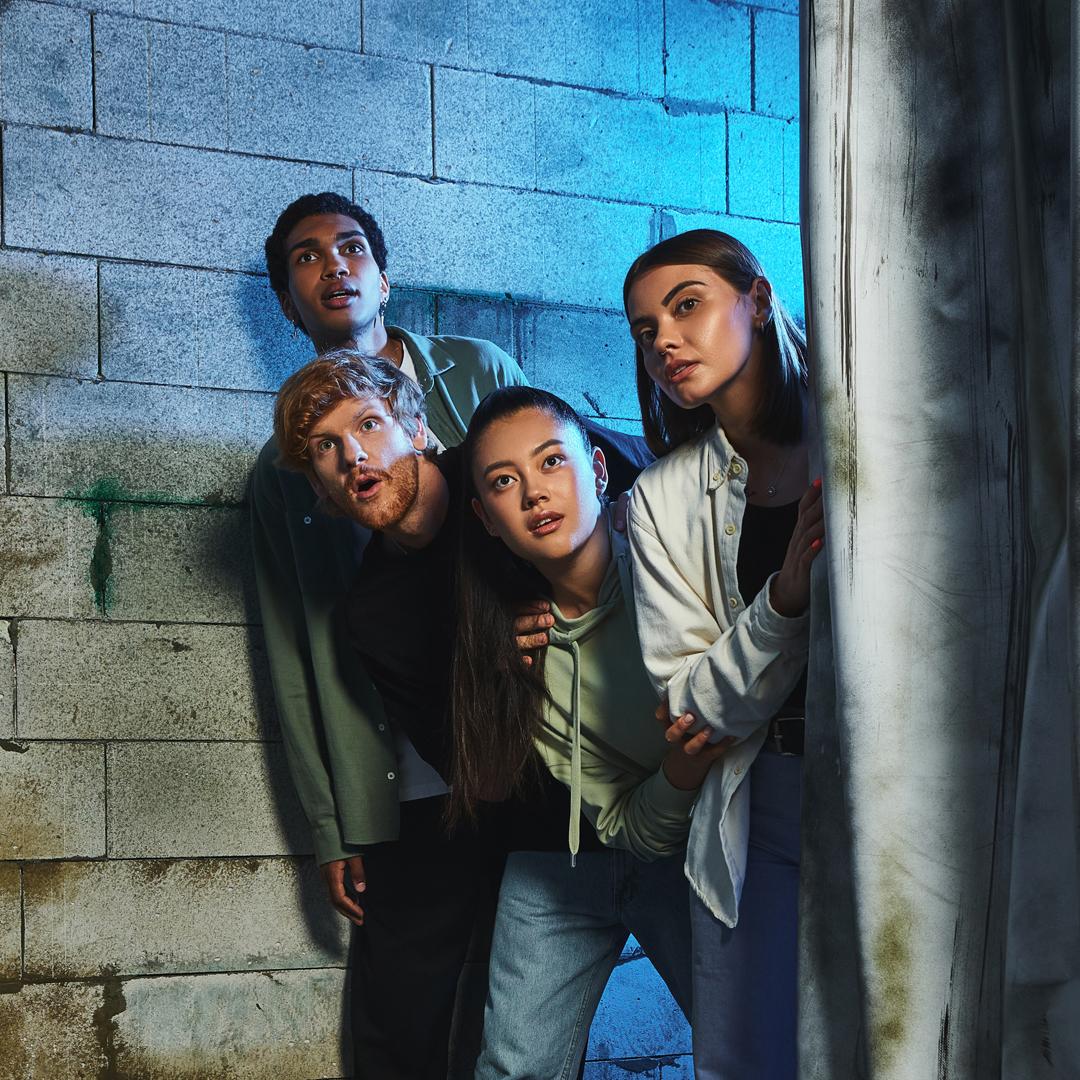 Four teens looking out behind wall