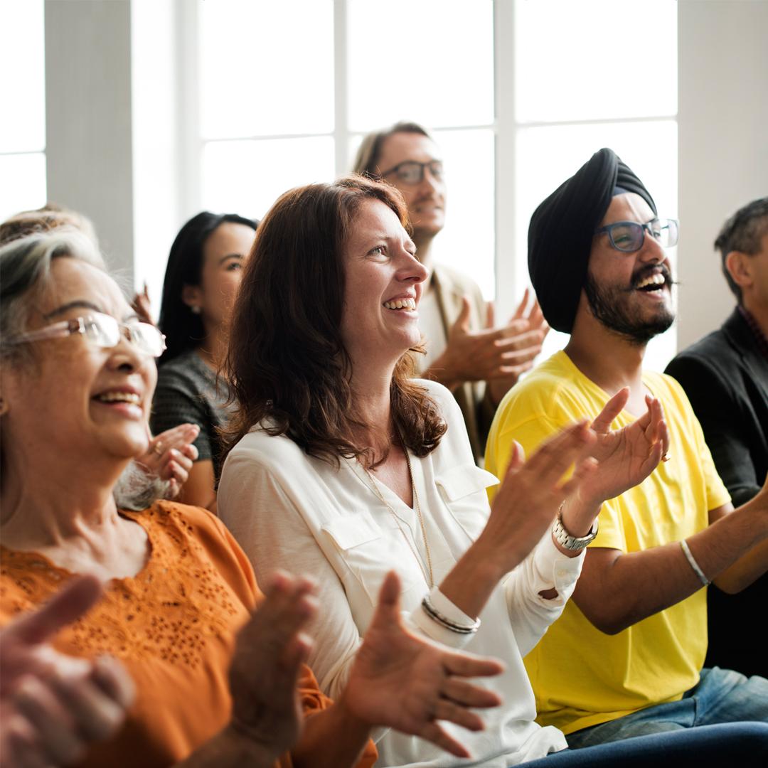 Seated audience clapping and smiling