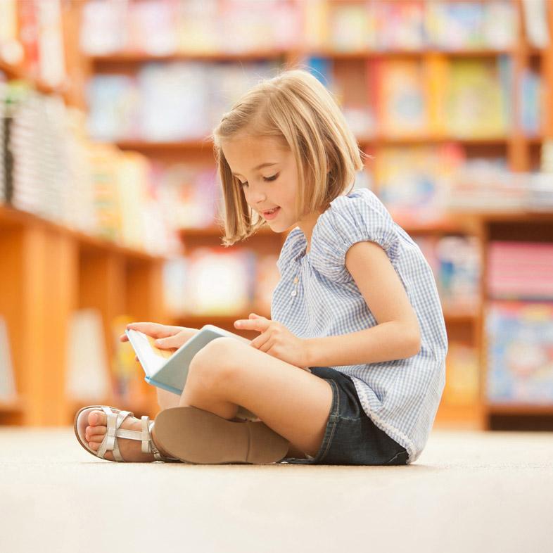 young girl reading book on the floor