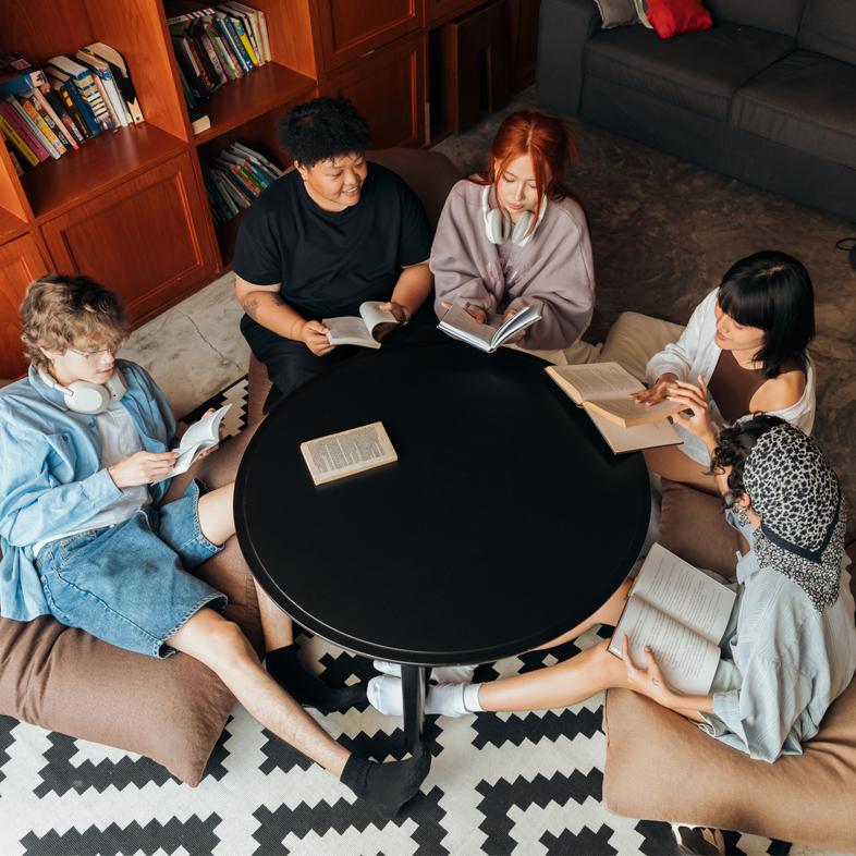College students sitting around table holding books