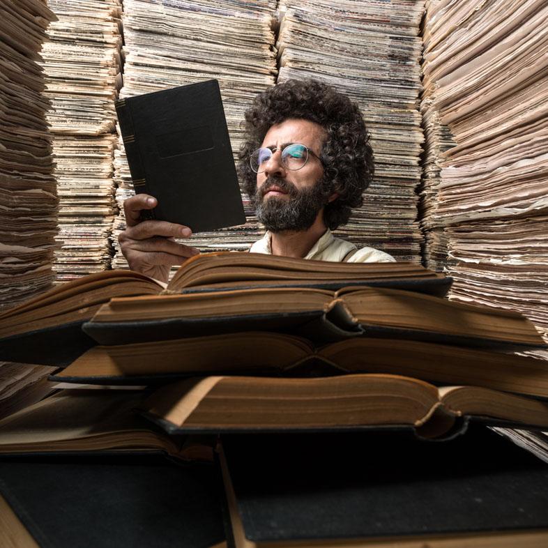 Man reading iPad surrounded by stacks of papers