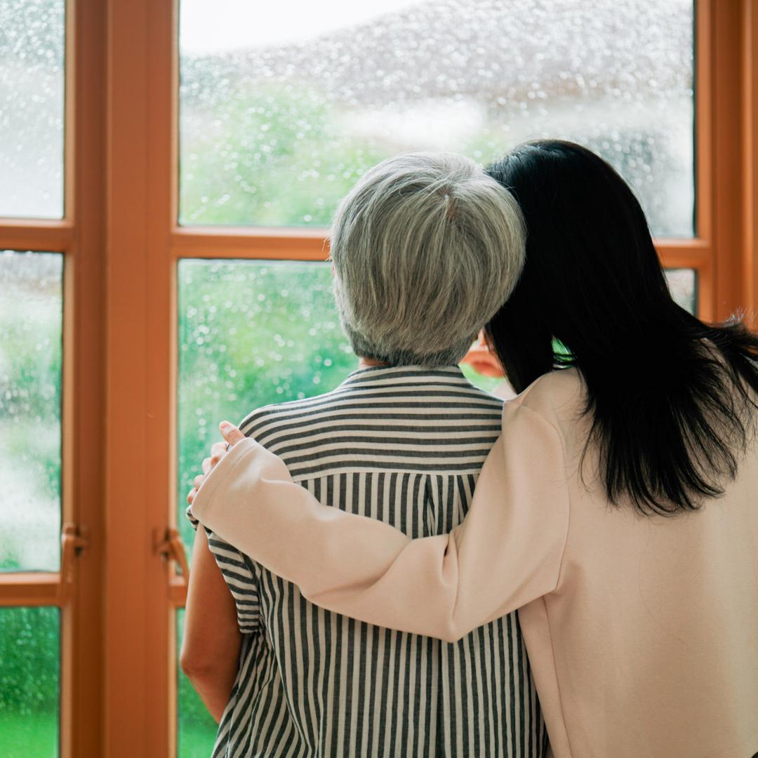 Senior woman and caregiver looking out window