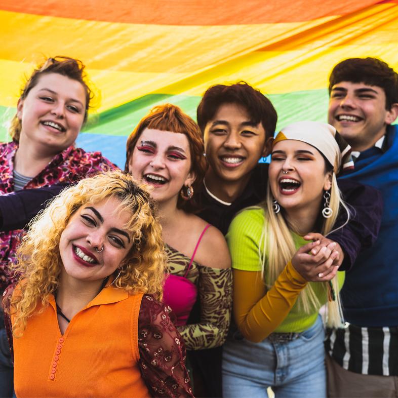 Group of teens smiling with pride flag
