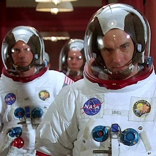 3 actors walking in space suits in NASA hallway