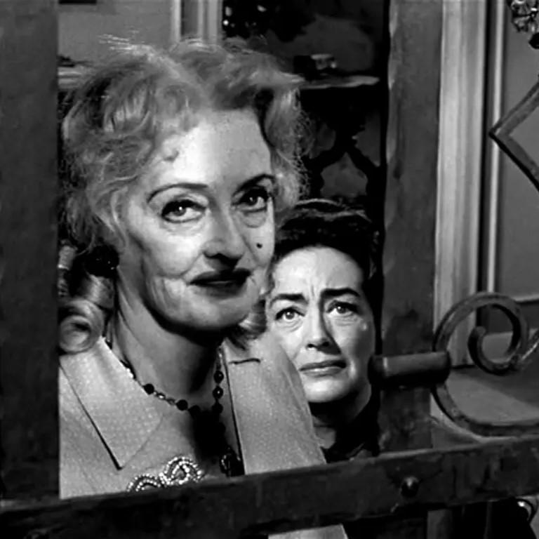 Actress Bette Davis at window with Joan Crawford behind