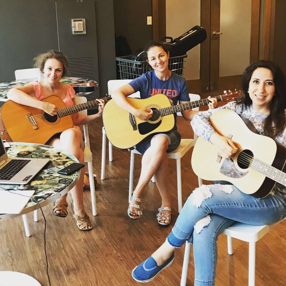 3 young women playing acoustic guitars