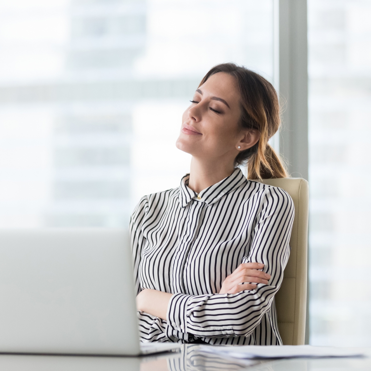 Woman looking up from computer with eyes closed