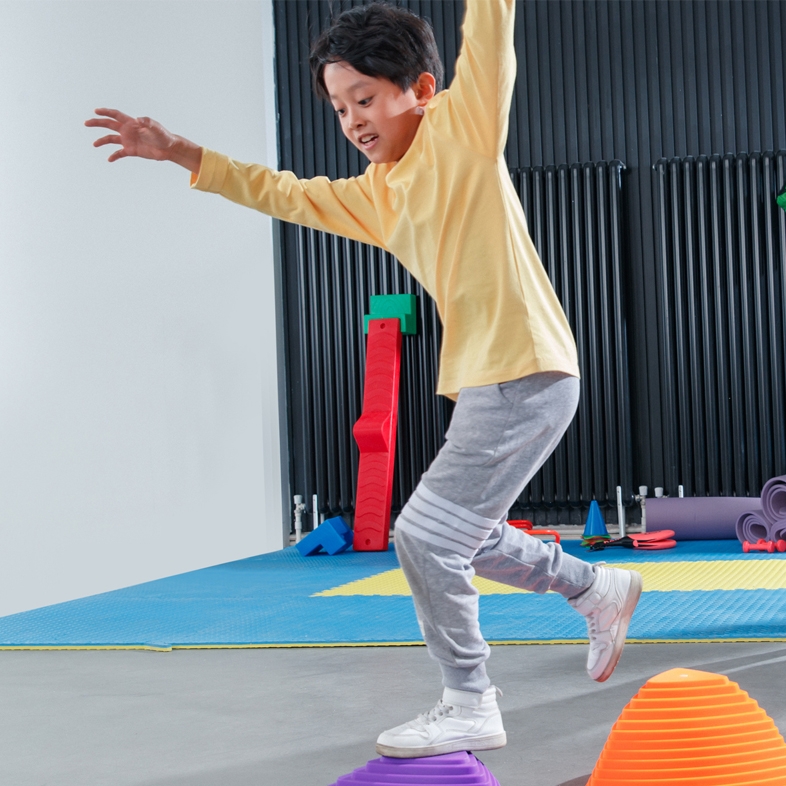 Child jumping onto raised surface with hands up