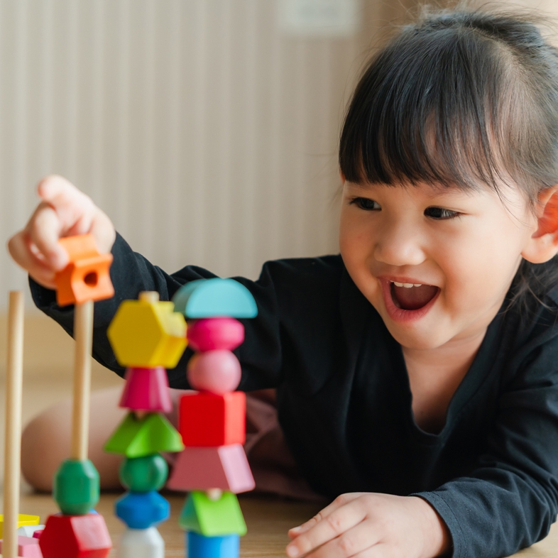 Young girl putting blocks on a post