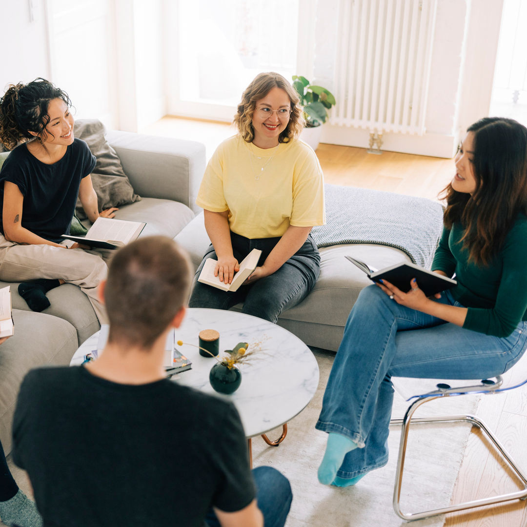 Group of adults sitting around a table discussing a book