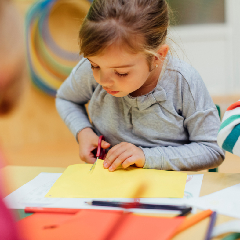 Child cutting a piece of paper with scissors