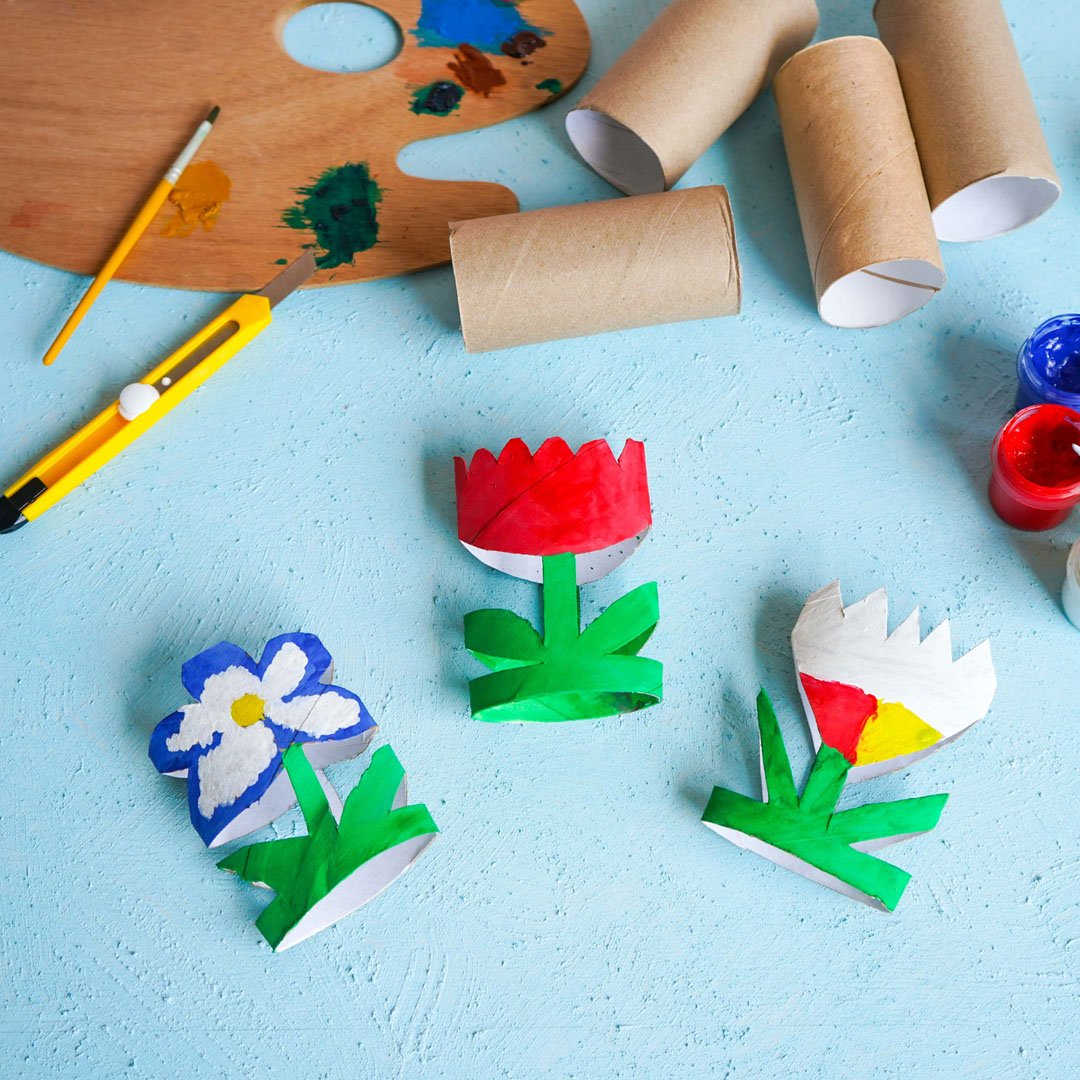 Paper flowers surrounded by paint and paper rolls