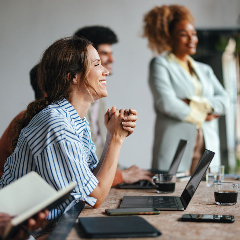 woman at a meeting looking up from laptop smiling