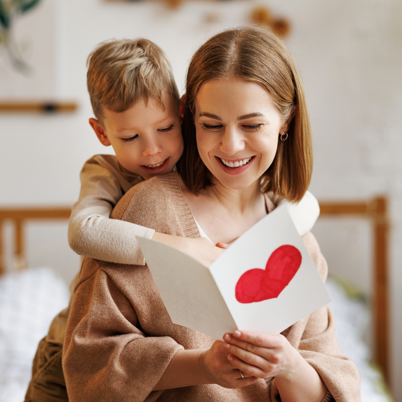 Mom reading a handmade card with child looking over her shoulder